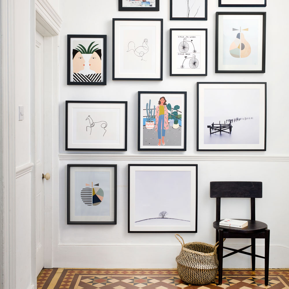 white hallway with gallery wall of blacked framed artworks