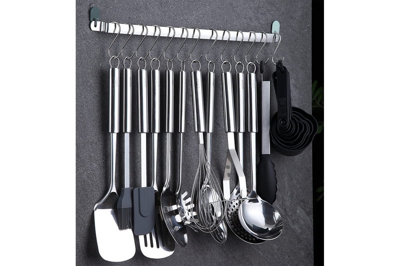Kitchen utensils hanging on a stainless steel pegboard.
